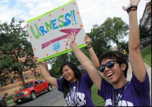 Staff in matching shirts hold sign pointing to Urness hall