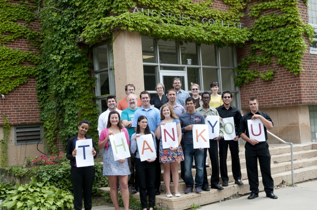 Group of Auggies stands in front of Old Science, those in front hold signs which together spell "thank you"