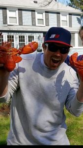 Jason Kusiak looking excited while holding two bright red lobsters.