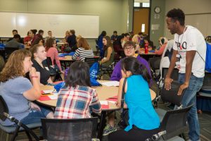 Osman with TRiO/SSS students at Normandale. Osman stands to talk to a round table full of students