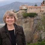 Lori Moline smiles with a cliffside chateau in the background