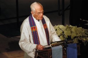 Phil Quanbeck in robes speaking at a podium