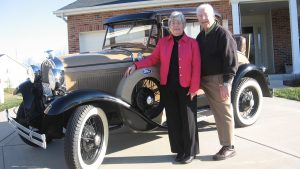 The Egertsons stand in their driveway with their collector car