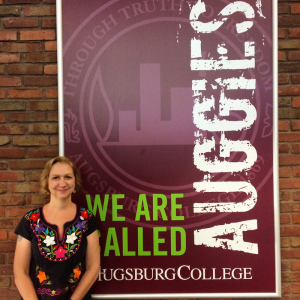 a woman stands in front of an Augsburg sign