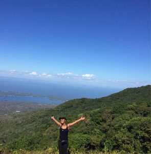 Student with arms open on a hillside