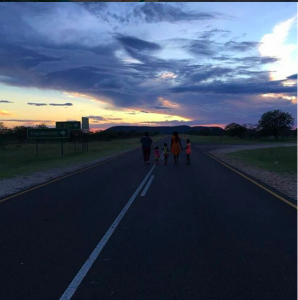 a family holds hands and walks down a road