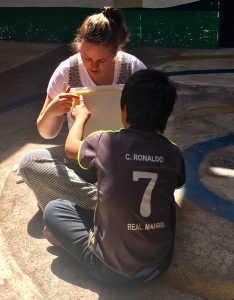 a young woman sits on the floor with a child reading a book together