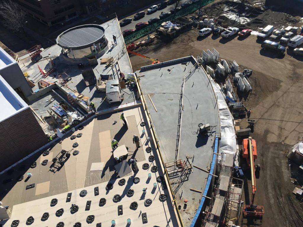 Crews install the final roofing layer on the west wing and around the suspended chapel.