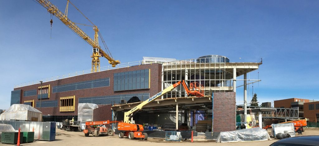 This view of the south side of the Hagfors Center shows the progress of the hand-laid brick on the flexible classroom and the structural framework for the lobby curtainwall.