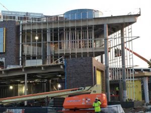 This south view of the Hagfors Center shows the suspended chapel, lobby curtainwall work, and the hand-laid brick of the flexible classroom wall.