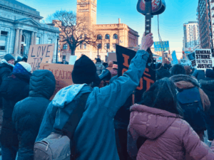 a protestor holds up a guitar in a march protesting ICE actions in MN