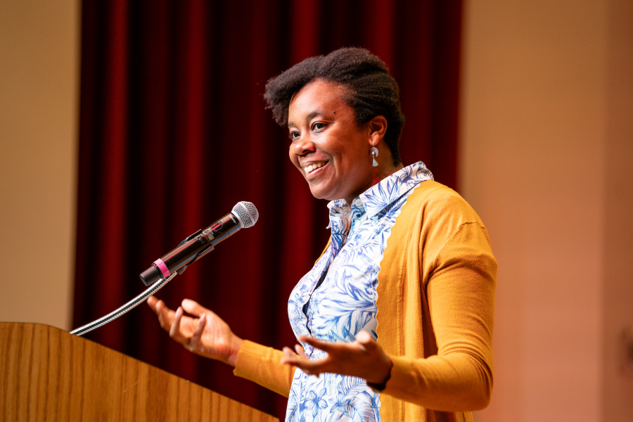 Rev. Jen Bailey is speaking and wearing bright yellow