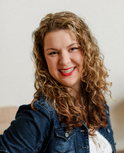 A woman with golden brown curly hair is smiling