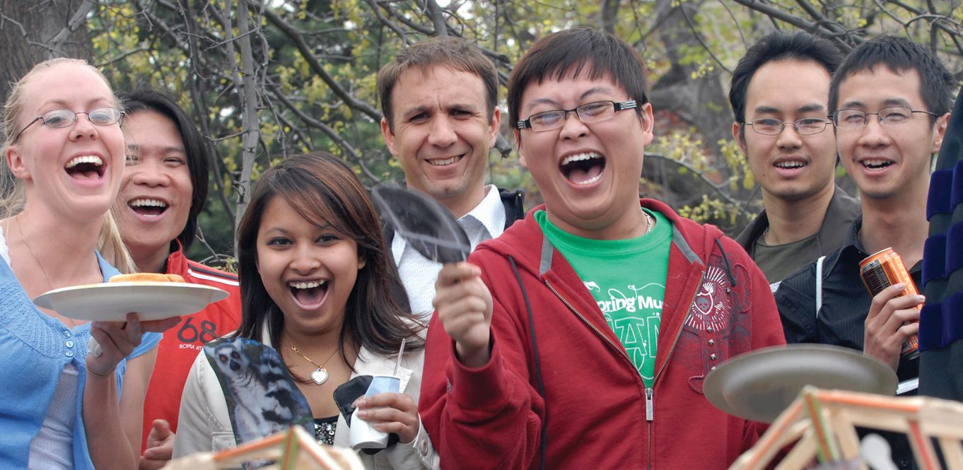 Five students with professors and staff completing science experiment.