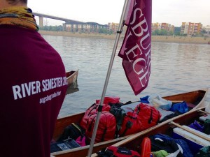 River semester canoes with gear and an Augsburg flag