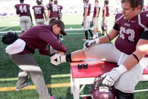 Head Athletic Trainer Missy Strauch assists offensive lineman Andrew Konieczny ’15 during Augsburg’s Homecoming football game.