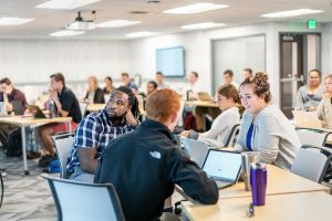 groups of students sit working collaboratively around room