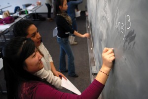 Calculus students working out problems on a blackboard. 