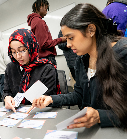 Two female students looking at notecards in a classroom.