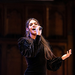 A student dressed in a black dress singing solo at Advent Vespers