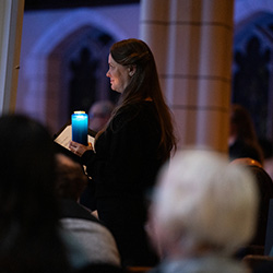 A women walking down the aisle holding a candle