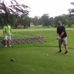 Two golfers watch as one swings