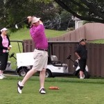 Eric Rolland swings while other golfers watch