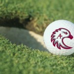 golf ball with Auggie Eagle logo next to a hole