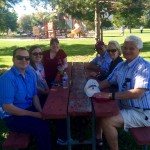 Augsburg alumni sit at a picnic table with Katie (Koch) Code