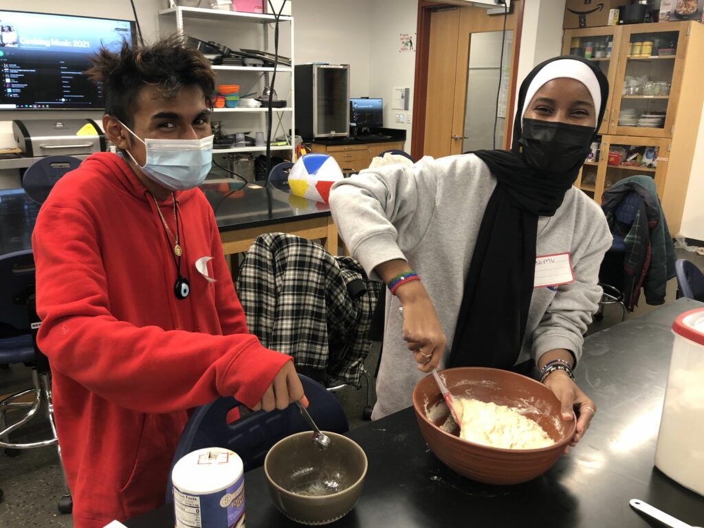 Two high schooler's mix ingredients in large bowls