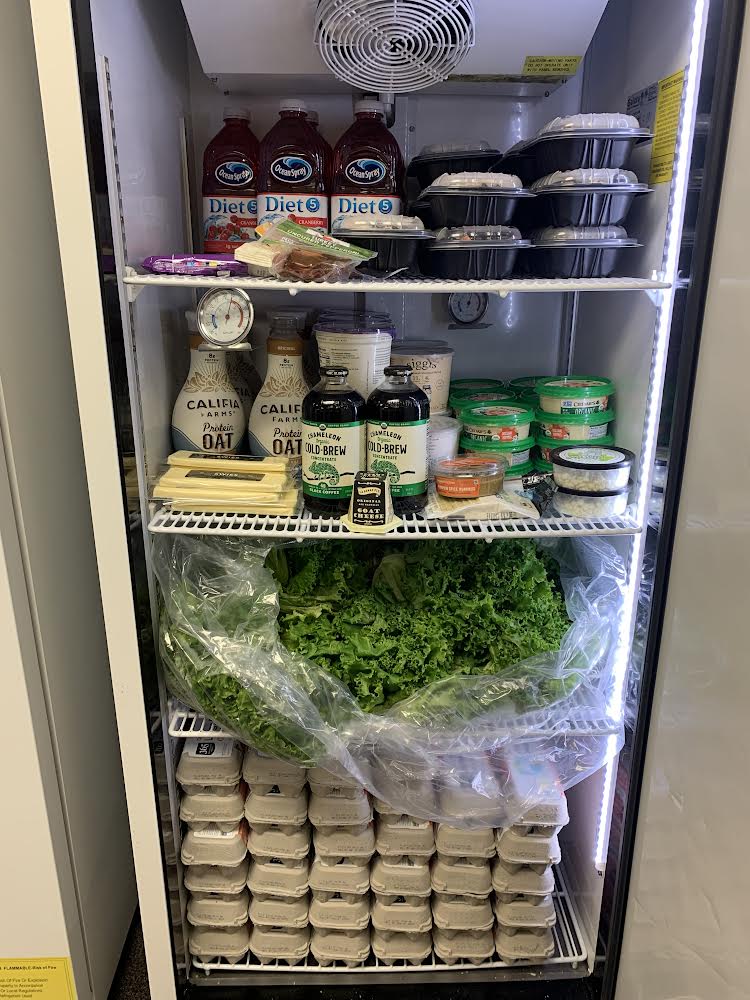 A fridge full of a variety of foods, including lettuce, eggs, microwavable meals, and beverages.