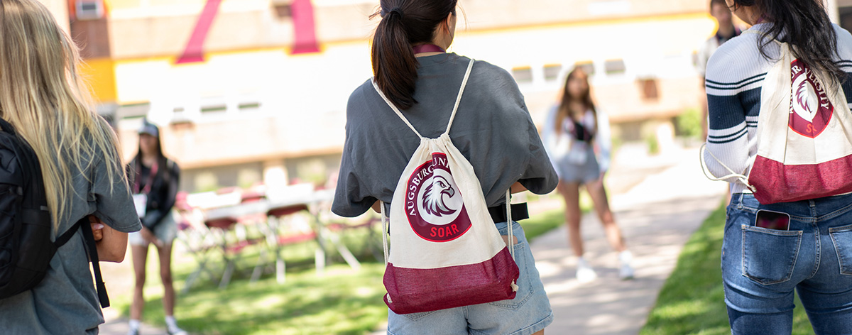 Three girls with backpacks standing with their backs to the camera.
