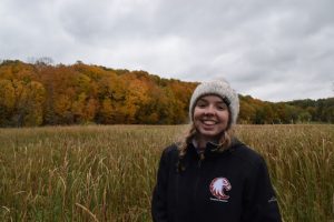 Grace Porter smiling and standing in a field in the fall