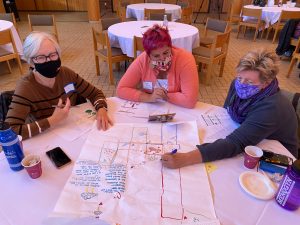 Three people sitting at a table with a map of their neighborhood on the table