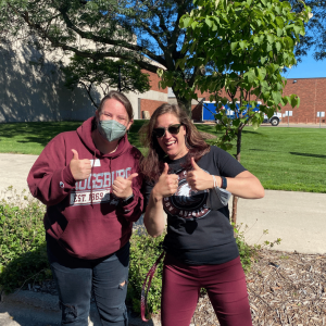 Amanda and Adrienne giving thumbs up outside on 7 1/2 street waiting for students to pass by on convocation day.