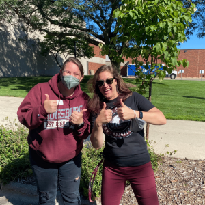 Amanda and Adrienne giving thumbs up outside on 7 1/2 street waiting for students to pass by on convocation day. 