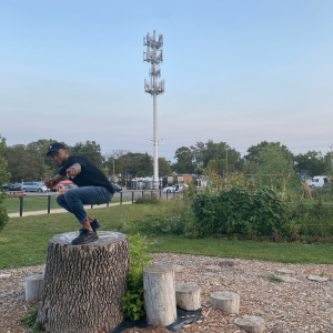 Geoffrey on a tree stump pointing at the camera