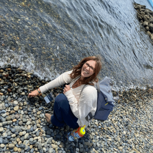 Kristina bending down picking rocks on the Seattle coast. 