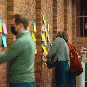 Young Adults posting their consolations written on post it notes on the wall of the chapel.