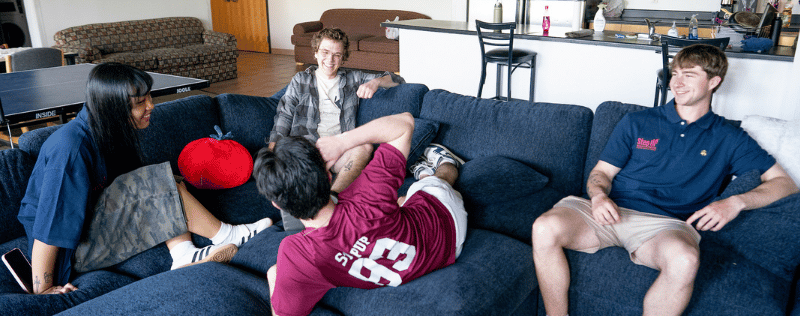4 StepUP students laughing on a couch together in Oren Gateway Center