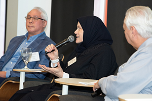 Panel discussion with three seated individuals, one speaking into a microphone.