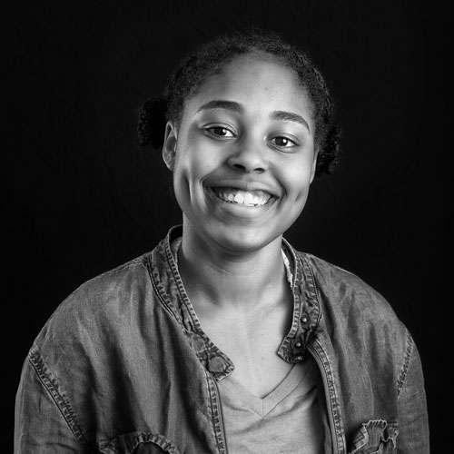 Black and white portrait of a smiling young woman with two buns, wearing a casual jacket.