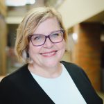 Kathy Hansen smiles for a photo in front of a blurred background