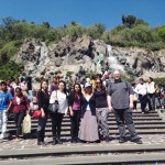 group pose on steps with waterfall and statue in background