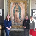 Students stand in front of a painting of the Virgin Mary