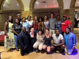 a group of 17 people smiles together in a group pose for the camera in a dining hall