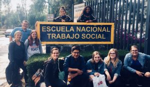 students pose by a sign that reads escuela nacional trabajo social