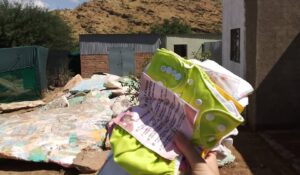 Reusable cloth diapers held up against the community backdrop in Windhoek