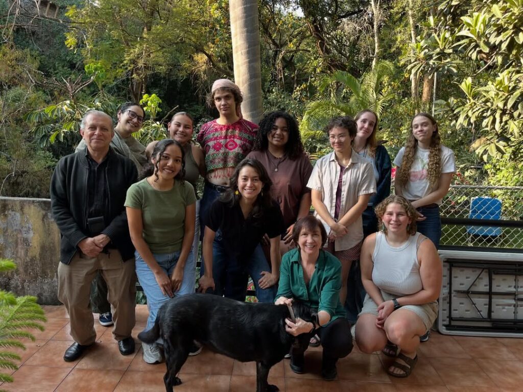 college students with three staff together outside smiling as a group
