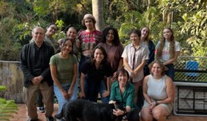 college students with three staff together outside smiling as a group